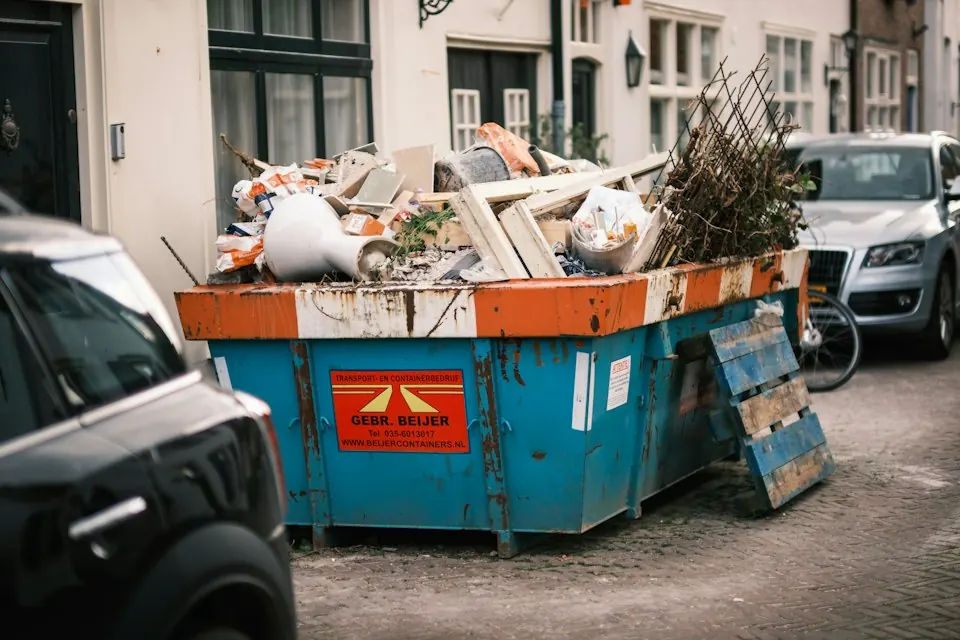 Blau-oranger Container mit Bauschutt am Straßenrand