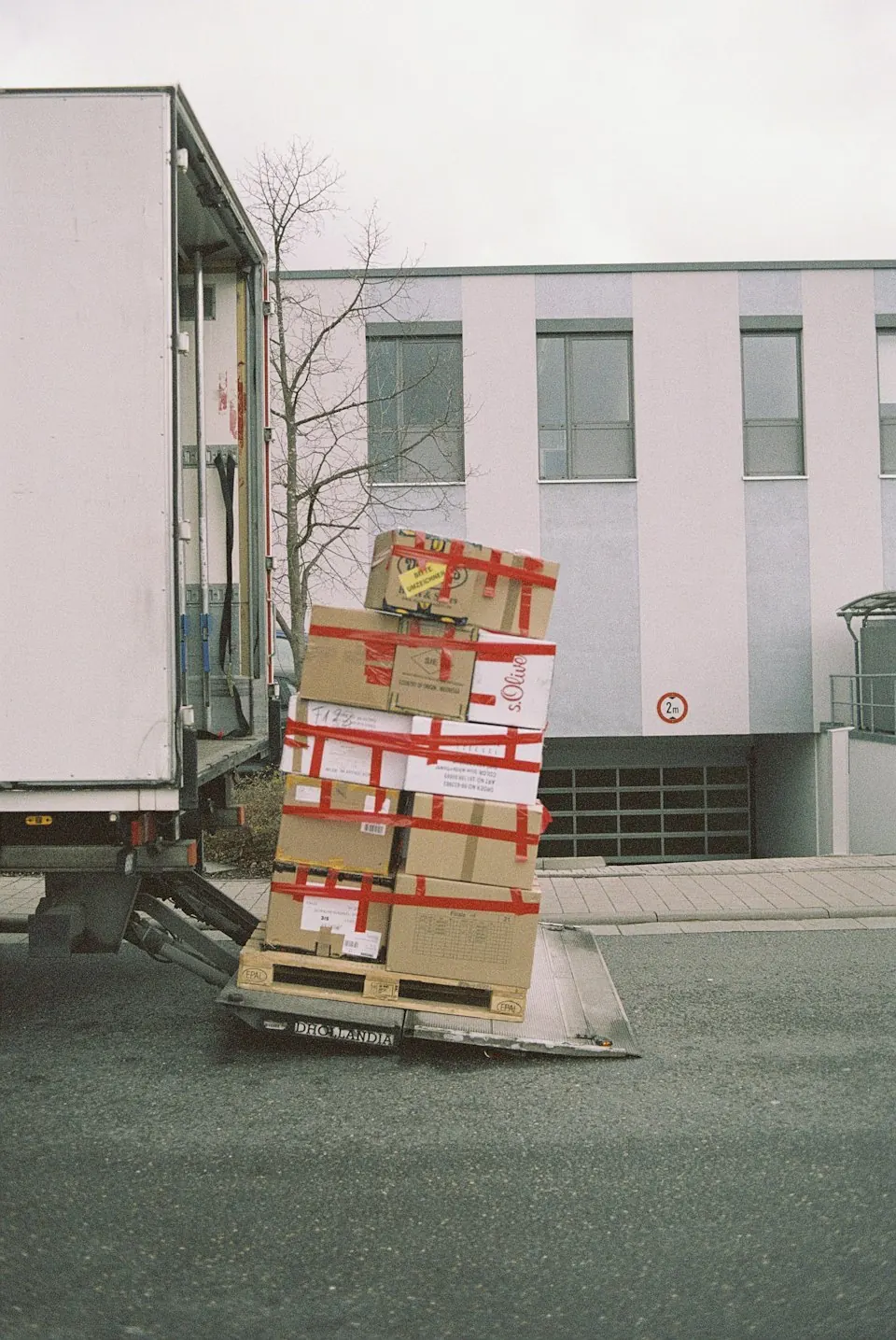 Gestapelte Kartons neben einem Transporter vor einem Gebäude